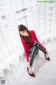 A woman in a red top and black leggings sitting on the floor.