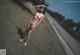 A naked woman standing on the side of a road.