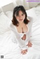 A woman in a white shirt is sitting on a bed.