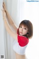 A woman in a red and white top leaning against a wall.