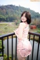 A woman in a pink dress standing on a balcony.