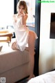 A woman in a white dress sitting on a couch.