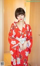 A woman in a red kimono standing in front of a door.