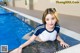 A woman in a blue and white shirt is sitting by a swimming pool.