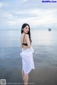 A woman standing in the water with a boat in the background.