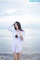 A woman in a white shirt standing on the beach.