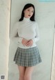 A woman in a white shirt and plaid skirt posing for a picture.