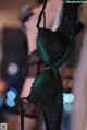 A woman wearing a green bra and black lingerie.