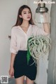 A woman holding a plant in a hanging light.