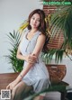 A woman sitting on top of a wooden table next to a plant.