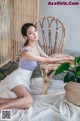 A woman sitting on a chair next to a potted plant.