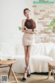 A woman standing in front of a white couch.