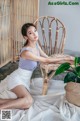 A woman sitting on a chair next to a potted plant.