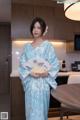 A woman in a blue and white kimono holding a fan.