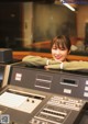 A woman leaning on a mixing desk in a recording studio.