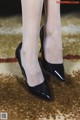 A close up of a woman's legs wearing black shoes.