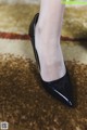 A close up of a woman's legs wearing black shoes.