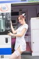 A woman in a nurse uniform standing in front of an ambulance.