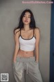 A woman in a white top and gray sweatpants posing for a picture.