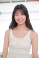 A woman in a white tank top smiles at the camera.