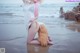 A woman with pink hair is sitting on the beach.