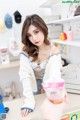 A woman sitting at a desk holding a cup of ice cream.