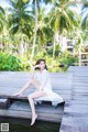 A woman in a white dress sitting on a wooden dock.