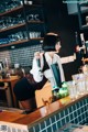 A woman standing behind a bar holding a beer tap.