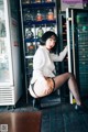 A woman in a white shirt and black stockings posing in front of a refrigerator.