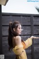 A woman in a yellow dress standing in the rain.