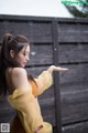 A woman in a yellow dress standing in the rain.