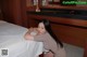 A woman leaning on a bed in a hotel room.