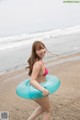 A woman in a bikini holding an inflatable ring on the beach.