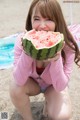 A young girl eating a watermelon on the beach.