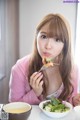 A woman sitting at a table eating a salad.