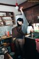 A woman standing in a kitchen holding a brown bag.