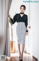 A woman standing in front of a door wearing a black and white skirt.