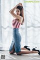 A woman in a red and white striped top and blue denim skirt.