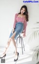 A woman sitting on a stool wearing a red and white striped top.