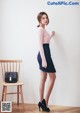 A woman standing next to a wooden chair in a room.