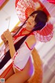 A woman in a red and white outfit holding an umbrella.