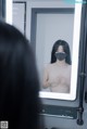 A woman wearing a face mask looking at herself in the mirror.