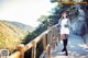 A woman standing on a wooden bridge in a white dress.