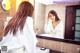 A woman in a bathrobe looking at herself in the mirror.