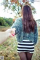 A woman holding the hand of a man in a striped skirt.