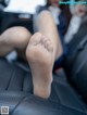 A woman sitting in the back seat of a car with her feet up.