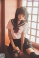 A woman in a school uniform sitting on a window sill.